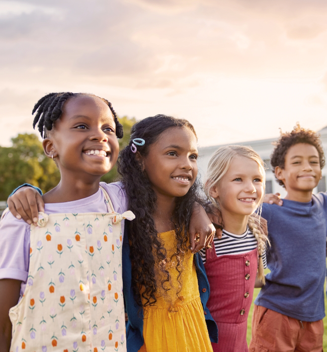 Four children standing outside, smiling after receiving care from Board-Certified Pediatric Specialists.